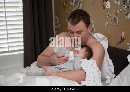 Papa Fütterung Baby im Bett Stockfoto