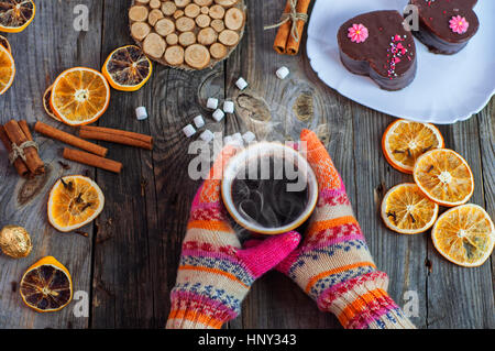 Tasse schwarzen Kaffee in ihren Händen tragen bunte Winterhandschuhe an Händen, Ansicht von oben Stockfoto