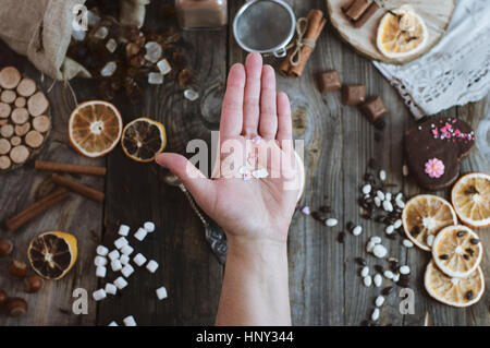 Offenen menschlichen Handfläche auf den Hintergrund der Tabelle mit Süßigkeiten, hält eine Prise Herz Stockfoto