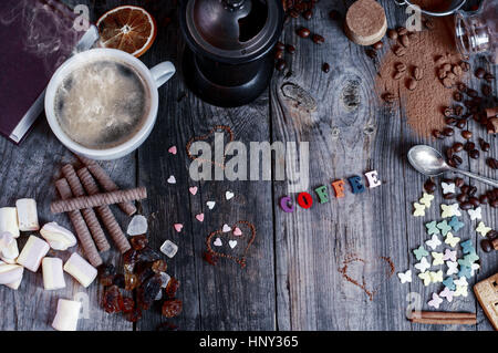 Zusammenfassung Hintergrund mit Süßigkeiten und eine Tasse schwarzen Kaffee auf einer grauen hölzernen Oberflächen, Top Sicht Stockfoto