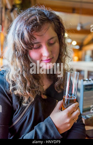 Junge Frau Mädchen halten und Verkostung blasses helles Bier aus Glas in rustikalen bayerischen Holzbar Stockfoto