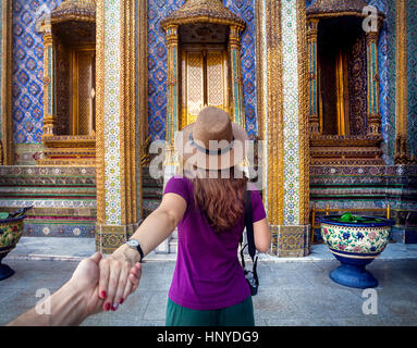 Frau in Hut und lila T-shirt Hauptdarsteller von Hand zum Wat Phra Kaew berühmten Tempel in Bangkok, Thailand Stockfoto