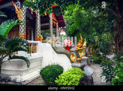 Frau Tourist mit roten traditionelle Thai Regenschirm im Tempel Kloster mit Drachen Statuen in Chiang Mai, Thailand Stockfoto