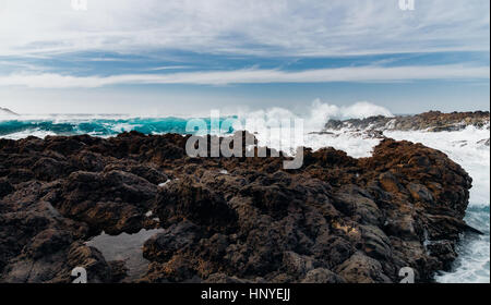 Malerische Felsenküste und riesige stürmischen Wellen gegen malerische Wolkengebilde Stockfoto