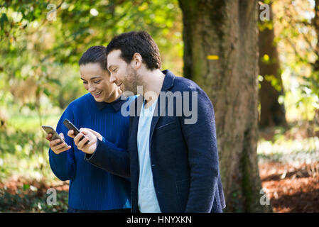 Paar mit Smartphones bei einem Spaziergang im Wald Stockfoto