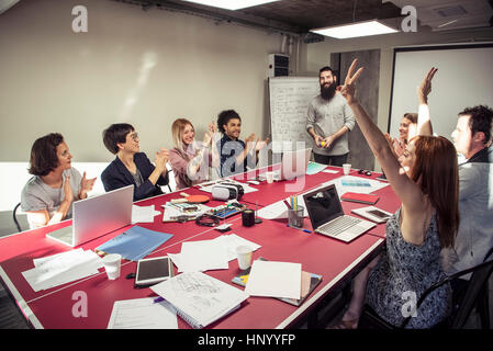 Kolleginnen und Kollegen feiern gute Nachricht während eines Meetings Stockfoto