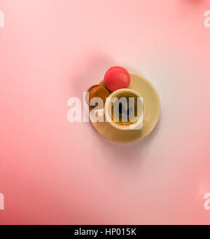 Schwarzen Kaffee in einer schönen Keramik Tasse mit zwei leckeren Macarons, rosa Stockfoto