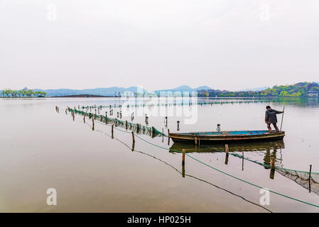 Chinesischer Mann auf einem Boot in der landschaftlich reizvollen Gegend der Westsee in Hangzhou Stockfoto