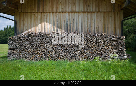 Stapel von gesägten Holzscheite unter Vordach des hölzernen Gebäude, Bad Kohlgrub, Ammergauer Alpen, Bayern, Deutschland Stockfoto