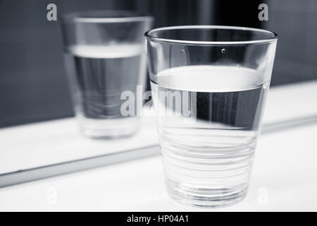 Glas Wasser stehen auf weißen Regal in der Nähe von Close-up Spiegel, schwarz / weiß Fotos Stockfoto