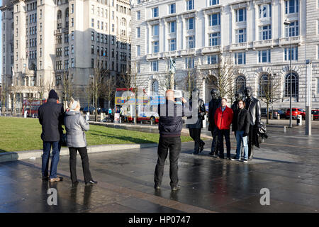 Touristen fotografieren mit der Beatles-Statue vor Pier head Wahrzeichen Gebäude Liverpool uk Stockfoto