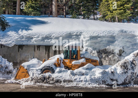 Ein großen gelben Schnee entfernen Frontlader Traktor ist mit Schnee bedeckt und hat Schnee in geschoben um ihn herum die effektiv macht es "eingeschneit." Stockfoto