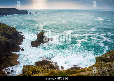 Mit Blick auf Wellen und die Irish Lady Felsformation Sennen Cove mit Lands End Cornwall in der Ferne. Stockfoto