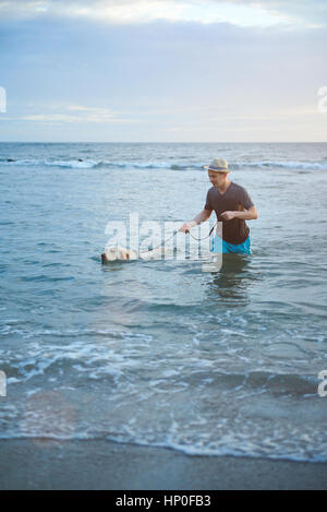 Mann mit Labrador Hund in Strand Meerwasser. Mann zu Fuß in Meerwasser mit Labrador Hund Stockfoto