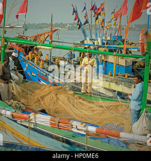 Netze für Schäden an Bord der Fischerboote im Hafen auf Diu Insel, Indien kontrolliert. Die Fischerei im arabischen Meer ist ein wichtiges Standbein der lokalen Wirtschaft Stockfoto