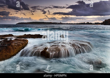 Offene Meer Surf Überlauf oben Strand Seite Felsen bei Ebbe in der Nähe von Freshwater Strand in Manly, Sydney. Farbenfrohen Sonnenuntergang Seelandschaft von Sydney Northern beach Stockfoto