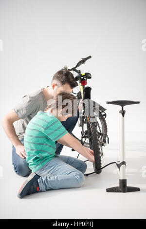 Vater und Sohn aufblasen Fahrrad Reifen mit Pumpe auf Stockfoto