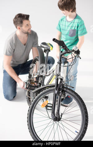 Glücklicher Vater und Sohn Aufpumpen von Fahrradreifen jeder Othe betrachten Stockfoto