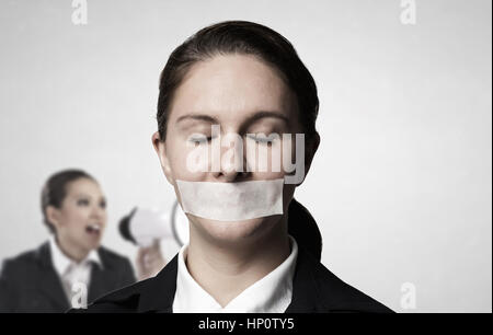 Junge Geschäftsfrau mit Klebeband auf Mund und müde Hände Stockfoto