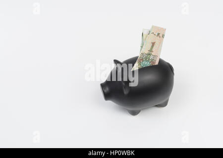 Schwarze Sparschwein mit chinesischer Yuan 1 Renminbi Banknote in Münzschacht platziert. Metapher für persönliche Ersparnisse oder chinesische Wirtschaft, China Schuldenkrise. Stockfoto