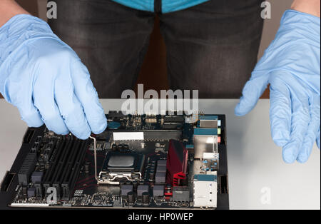 Junger Mann mit Handschuhen einstecken CPU auf Mainboard Sockel LGA-1151 Stockfoto