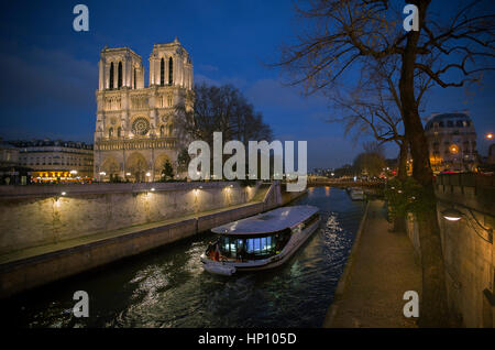 Ein Ausflugsschiff bewegt sich vorbei an Kathedrale Notre-Dame auf der Seine in der Dämmerung, Paris, Frankreich Stockfoto