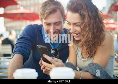 Paar auf der Suche auf Smartphone zusammen im freien Stockfoto