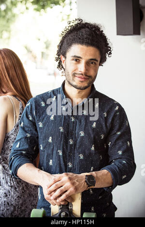 Junger Mann Betrieb Longboard, portrait Stockfoto