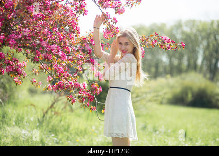 Schöne junge Mädchen schöne Smilling und genießen warme Tag im Park während der Kirschblüte an einem schönen Frühlingstag Stockfoto