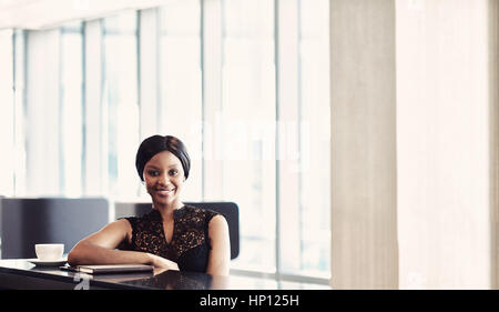 Schwarz erfolgreiche Geschäftsfrau in Kamera sitzen am Schalter Stockfoto