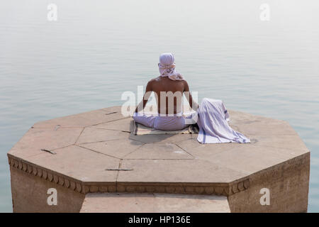 Ein Mann meditiert über den Ganges in Varanasi, eine der heiligsten Städte Indiens. Varanasi ist ein beliebtes Ziel für Touristen, die Teilnahme an Yoga-Schulen. Stockfoto