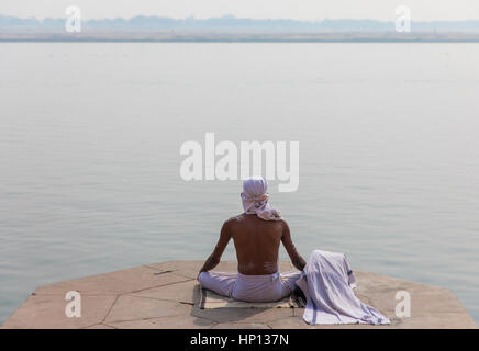 Ein Mann meditiert über den Ganges in Varanasi, eine der heiligsten Städte Indiens. Varanasi ist ein beliebtes Ziel für Touristen, die Teilnahme an Yoga-Schulen. Stockfoto