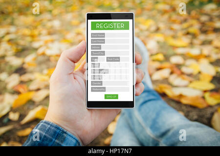 Mann im Park Anmeldeformular in sein Handy suchen. Alle Bildschirm-Grafiken bestehen. Stockfoto