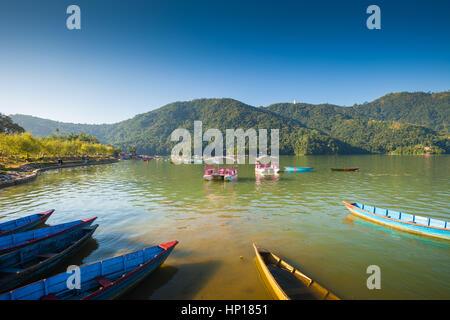 Ruderboote aufgereiht am Fewa Lake (Phewa Tal), Pokhara, Nepal mit Machhapuchre im Hintergrund Stockfoto