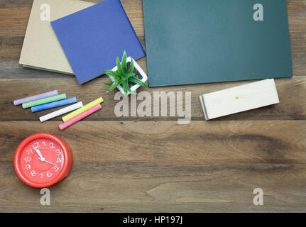 Rote Uhr, bunte Kreiden, Chalk Board, Buch und Radiergummi auf hölzernen Hintergrund Stockfoto