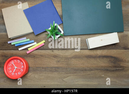 Rote Uhr, bunte Kreiden, Chalk Board, Buch und Radiergummi auf hölzernen Hintergrund Stockfoto
