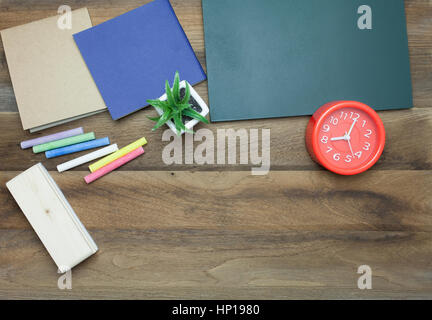 Rote Uhr, bunte Kreiden, Chalk Board, Buch und Radiergummi auf hölzernen Hintergrund Stockfoto