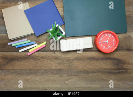 Rote Uhr, bunte Kreiden, Chalk Board, Buch und Radiergummi auf hölzernen Hintergrund Stockfoto