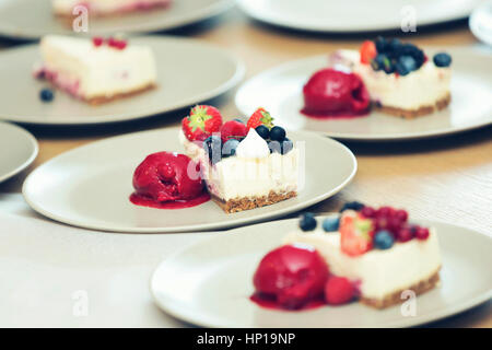 Käsekuchen mit Beeren und Sorbet auf Platten Stockfoto