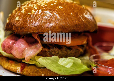 Hausgemachte frische Burger mit Speck auf einer hölzernen Platte-Nahaufnahme Stockfoto