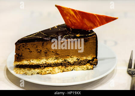 Karamell-Mousse mit Schokolade Topping Stück Kuchen auf einem weißen Tisch Stockfoto