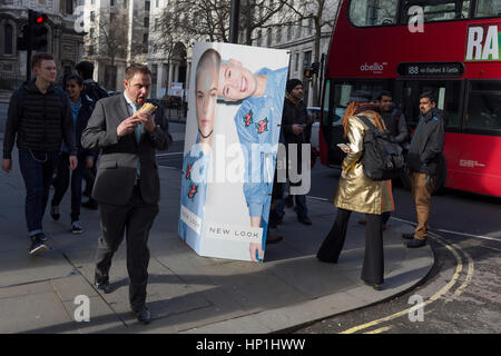 London, UK. 17. Februar 2017. London, UK. 17. Februar 2017. Ein Geschäftsmann geht und isst seine mittags-Sandwich-Outisde London Fashion Week in den Strang in London, Vereinigtes Königreich. London Fashion Week ist eine Kleidung Messe gehalten in London zweimal jährlich, im Februar und September. Es gehört zu den "Big Four" Fashion Weeks, zusammen mit New York, Mailand und Paris. Der Fashion-Branche spielt eine bedeutende Rolle in der Wirtschaft des Vereinigten Königreichs mit der sechstägige London Fashion Week allein zu jeder Jahreszeit £ 269 Millionen Scheffeln geschätzt. Bildnachweis: RichardBaker/Alamy Live-Nachrichten Stockfoto