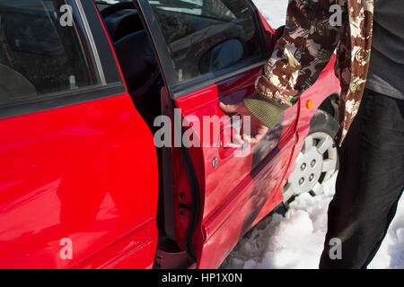 Der Mann hält den Griff und öffnet die Autotür Stockfoto