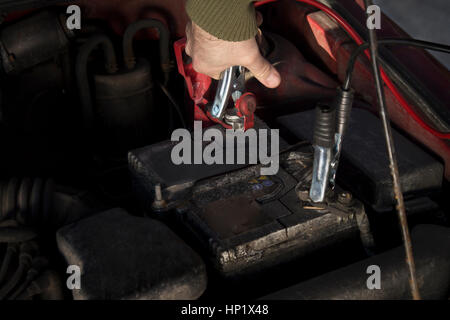 Eine entladene Batterie mit mechanischen Jumper-Kabel verbunden. Brennen das Auto im Winter durch die Jumper-Kabel. Stockfoto