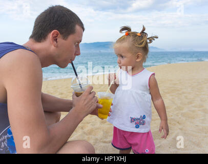 Vater und Tochter am Strand Saft zu trinken. Stockfoto