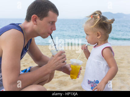 Vater und Tochter am Strand Saft zu trinken. Stockfoto