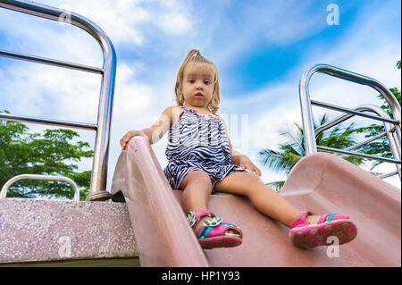 kleines Mädchen gilt für eine Fahrt auf einem Kinder-Hügel. Stockfoto