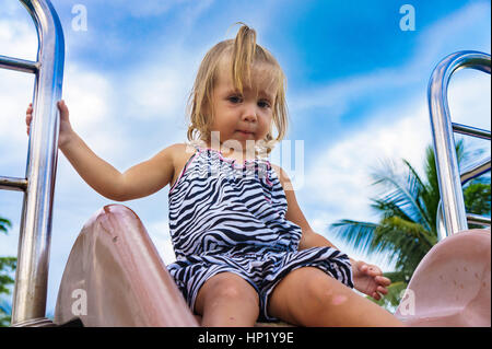 kleines Mädchen gilt für eine Fahrt auf einem Kinder-Hügel. Stockfoto