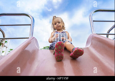 kleines Mädchen gilt für eine Fahrt auf einem Kinder-Hügel. Stockfoto