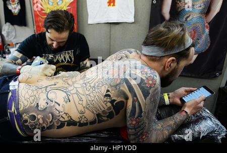 Neil Ayre liegt auf dem Bauch, wie Stewart Robson auf eine Tätowierung auf dem Rücken auf der kollektiven Tattoo Convention, verfügt über 150 Tattoo-Künstler arbeitet, die Old Truman Brewery in Ost-London. PRESS ASSOCIATION Foto Bild Datum: Freitag, 17. Februar 2017. Bildnachweis sollte lauten: John Stillwell/PA Wire Stockfoto